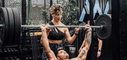Man lifting weights with woman spotting in Mexico City gym. Urban and dynamic fitness scene.