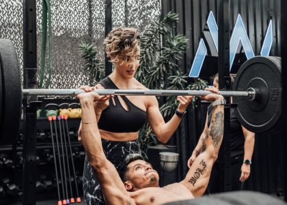 Man lifting weights with woman spotting in Mexico City gym. Urban and dynamic fitness scene.